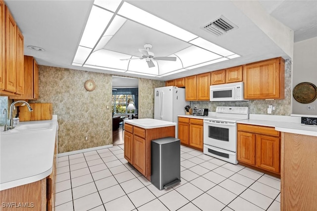 kitchen featuring ceiling fan, white appliances, a sink, visible vents, and a tray ceiling