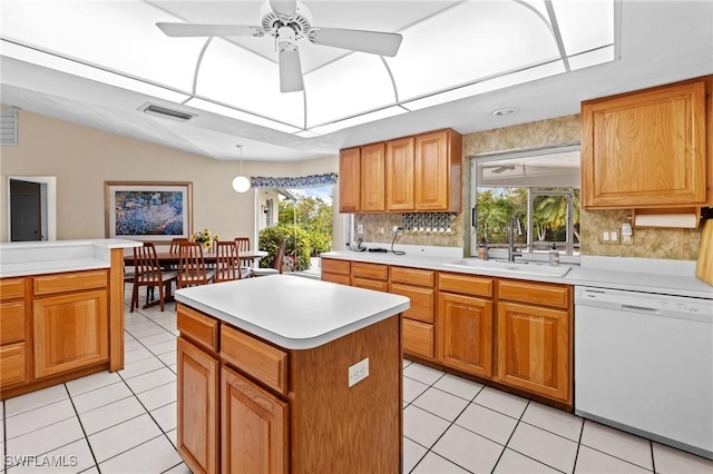 kitchen with light tile patterned floors, a center island, white dishwasher, light countertops, and a sink