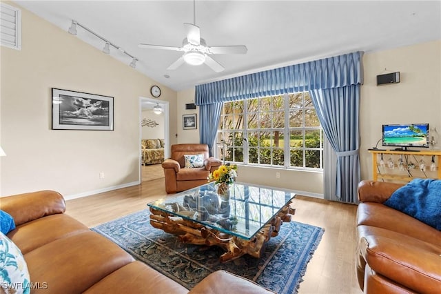 living room with lofted ceiling, ceiling fan, track lighting, wood finished floors, and baseboards