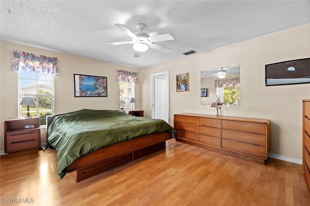 bedroom with baseboards, visible vents, ceiling fan, light wood-type flooring, and a closet