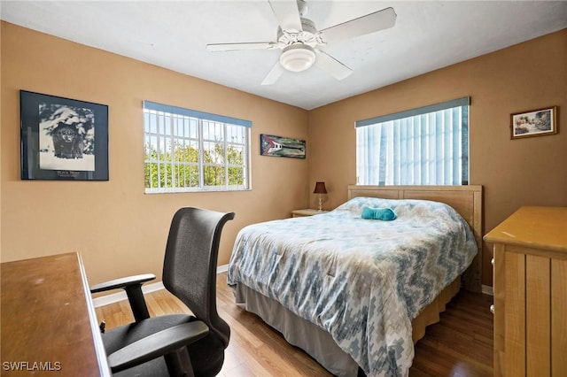 bedroom with a ceiling fan, baseboards, and wood finished floors