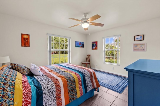 bedroom featuring multiple windows, tile patterned flooring, a ceiling fan, and baseboards