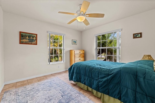 bedroom with a ceiling fan, multiple windows, baseboards, and light tile patterned floors