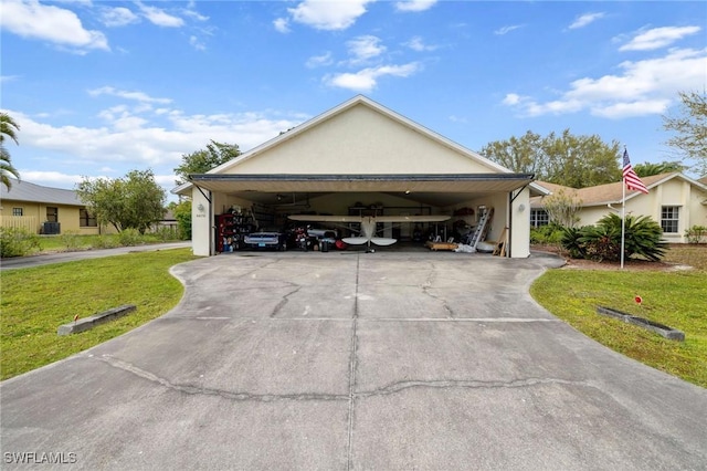 exterior space featuring a garage, concrete driveway, a front lawn, and stucco siding