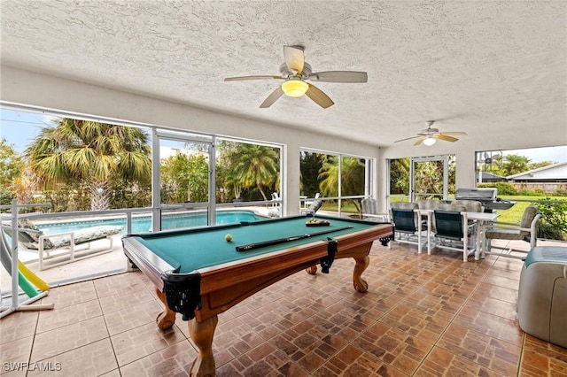 rec room with brick floor, pool table, a textured ceiling, and a ceiling fan