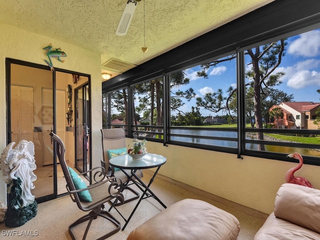 sunroom featuring a water view and a ceiling fan