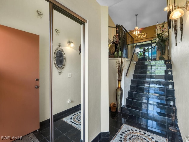 staircase with a ceiling fan, tile patterned flooring, and vaulted ceiling