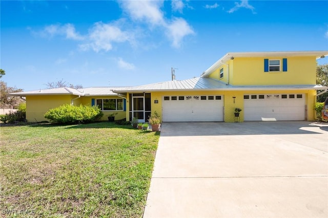 traditional home with metal roof, a front lawn, concrete driveway, and stucco siding