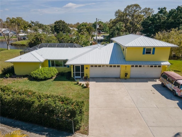 view of front of house with a front yard, concrete driveway, glass enclosure, and metal roof