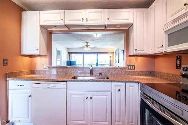 kitchen featuring white appliances, a ceiling fan, a sink, a textured ceiling, and white cabinetry