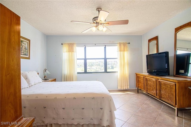 bedroom with a textured ceiling, light tile patterned flooring, and a ceiling fan