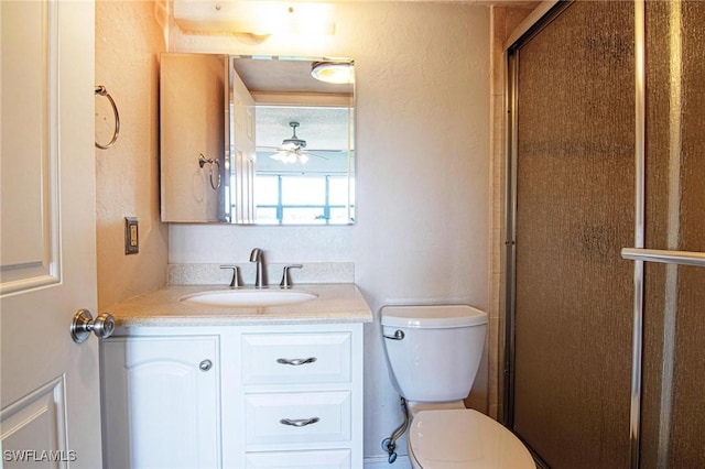 full bath featuring vanity, toilet, a textured wall, and a shower with door