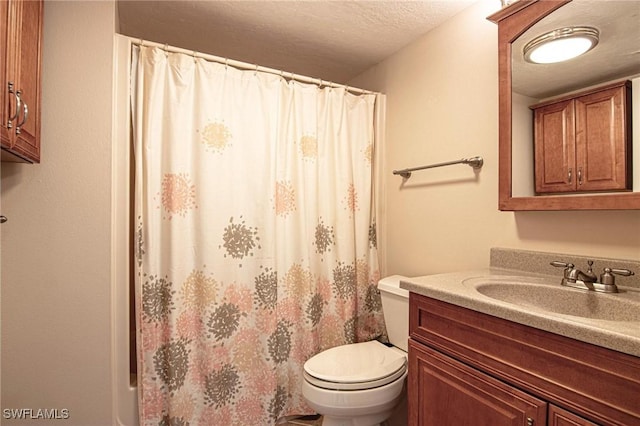 bathroom with a textured ceiling, vanity, and toilet