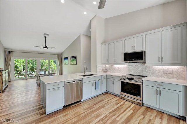 kitchen featuring ceiling fan, appliances with stainless steel finishes, a peninsula, light countertops, and a sink