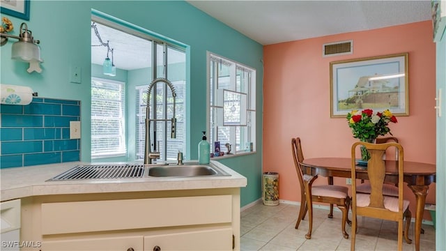 bathroom featuring baseboards, visible vents, a sink, tile patterned floors, and tasteful backsplash