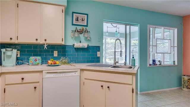 kitchen featuring tasteful backsplash, dishwasher, light countertops, light tile patterned floors, and a sink