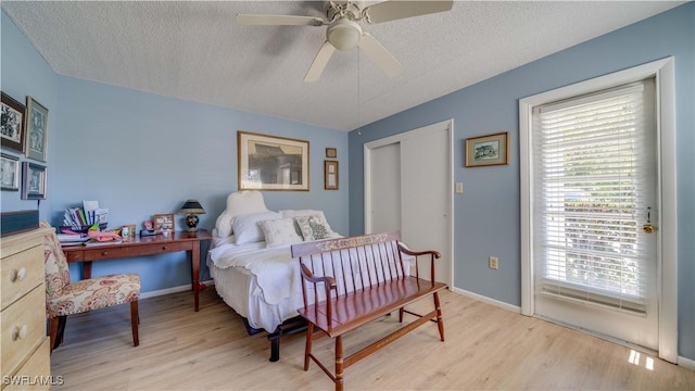 bedroom featuring baseboards, light wood-type flooring, and a textured ceiling