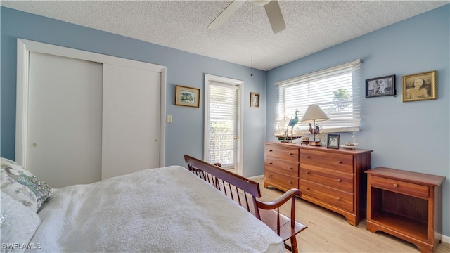 bedroom with a closet, light wood-style floors, a ceiling fan, and a textured ceiling