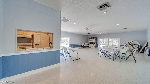 dining space featuring a wealth of natural light, visible vents, a textured ceiling, and speckled floor