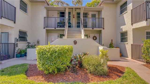 exterior space with stairway, stucco siding, and fence