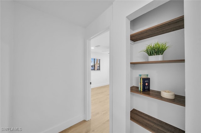 hall featuring light wood-type flooring and baseboards