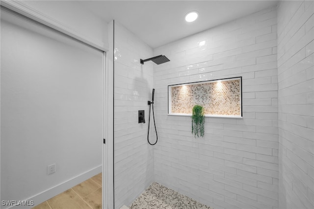 full bathroom with baseboards, a tile shower, and wood finished floors