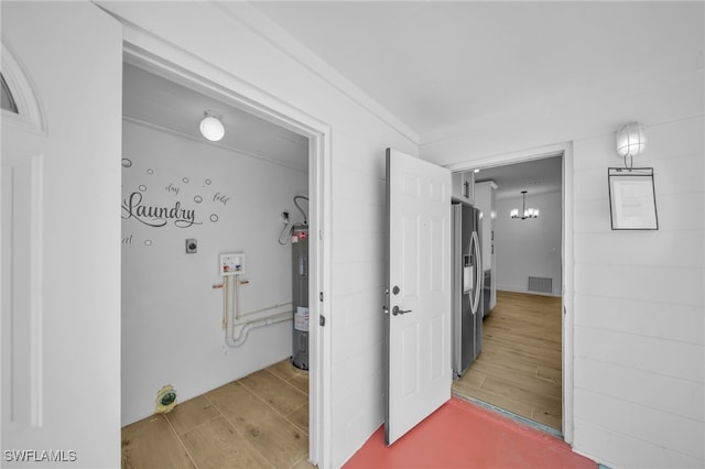 hall with light wood-type flooring, visible vents, a notable chandelier, and electric water heater