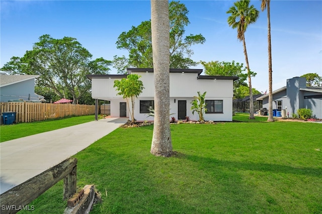 view of front facade featuring driveway, a front lawn, and fence