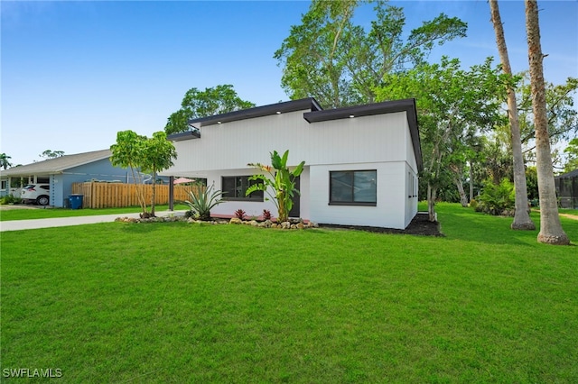 view of front of property with fence, a front lawn, and concrete driveway