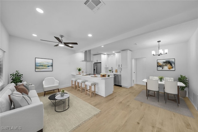 living area with ceiling fan with notable chandelier, light wood-type flooring, visible vents, and recessed lighting