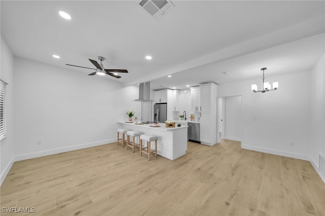 kitchen with light wood-style flooring, stainless steel appliances, a breakfast bar, visible vents, and wall chimney range hood