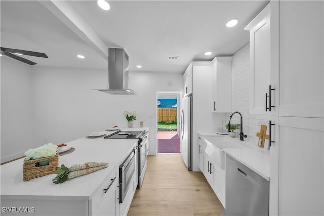 kitchen with a sink, white cabinetry, light countertops, appliances with stainless steel finishes, and island exhaust hood