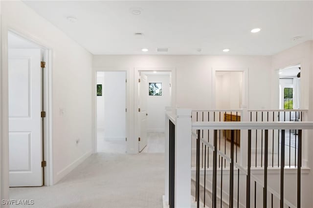 hall with recessed lighting, visible vents, light carpet, an upstairs landing, and baseboards