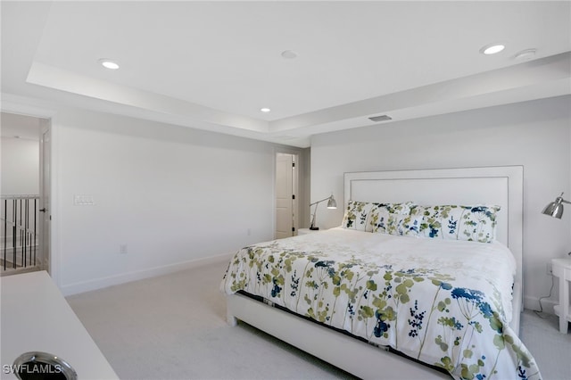 bedroom with recessed lighting, a raised ceiling, light carpet, and visible vents