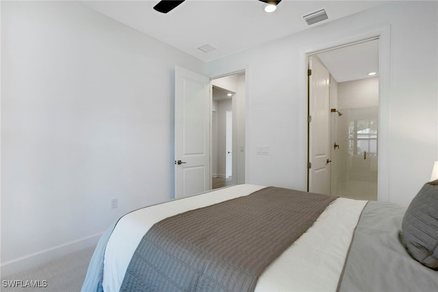 carpeted bedroom featuring ensuite bathroom, visible vents, and baseboards