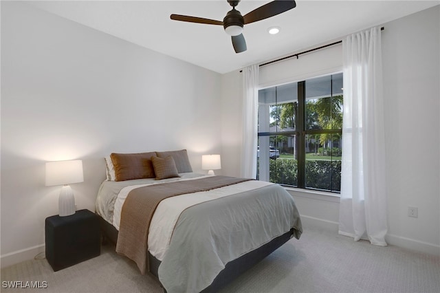 bedroom with ceiling fan, baseboards, and light colored carpet