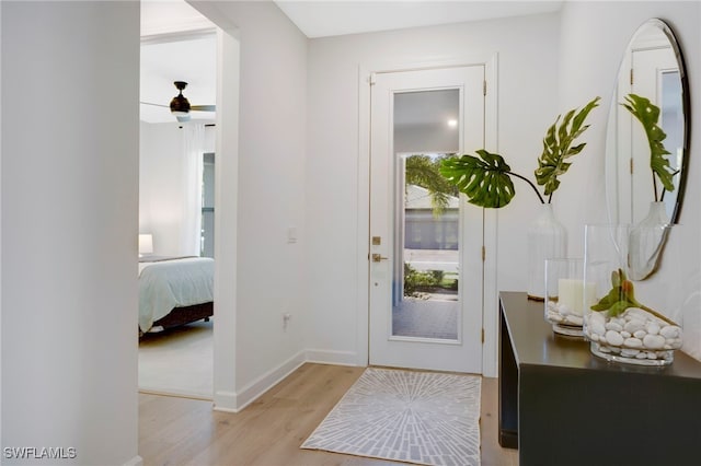 entryway featuring light wood-type flooring, a ceiling fan, and baseboards