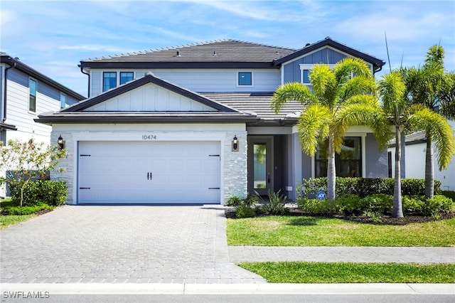 view of front of home with a garage, decorative driveway, board and batten siding, and a tiled roof