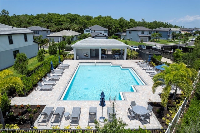 community pool with a patio area, fence, and a gazebo