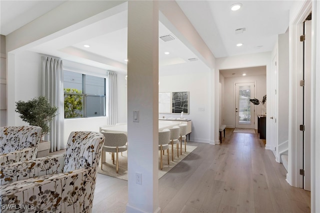 hallway with recessed lighting, plenty of natural light, visible vents, and light wood-style floors