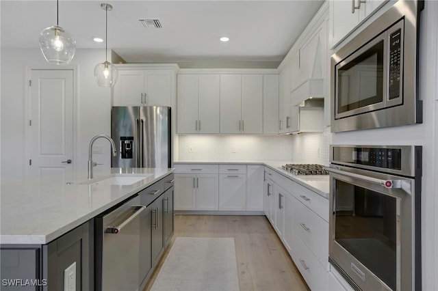 kitchen with tasteful backsplash, white cabinets, stainless steel appliances, light wood-style floors, and a sink