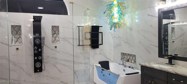 bathroom with tile walls, a marble finish shower, vanity, and a tub with jets