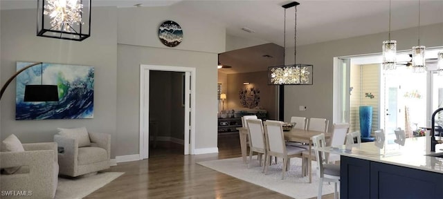 dining area featuring lofted ceiling, wood finished floors, visible vents, baseboards, and an inviting chandelier