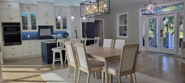 dining space featuring a chandelier, french doors, and light wood-style floors