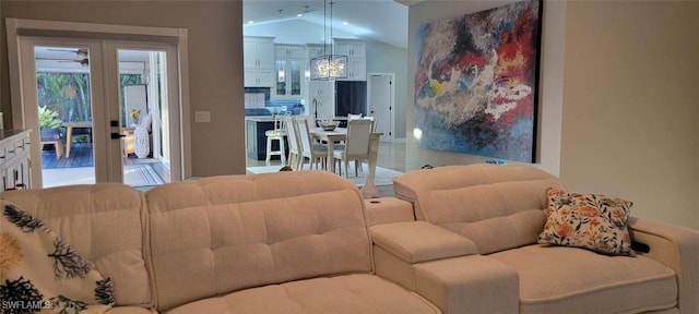 living room featuring a chandelier, vaulted ceiling, and french doors