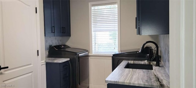 laundry area with washer and clothes dryer, a sink, and cabinet space