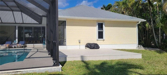 back of property with metal roof, glass enclosure, a yard, an outdoor pool, and a patio area