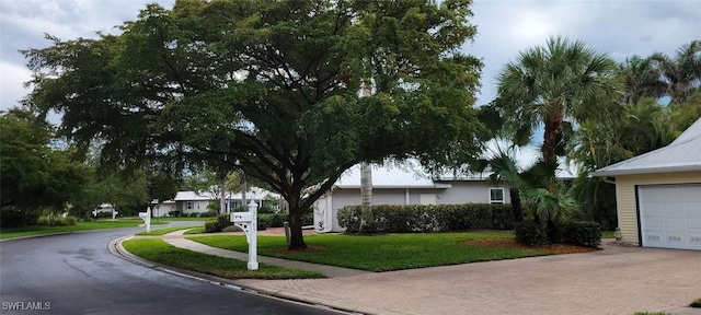 view of front of home with a garage, a front yard, and decorative driveway