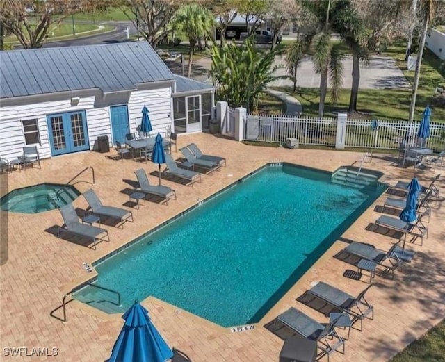 community pool featuring a patio, french doors, fence, and a hot tub