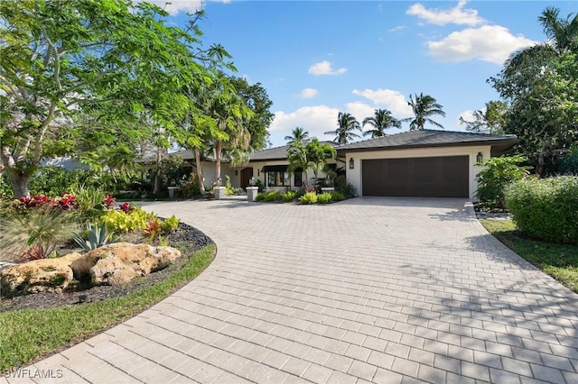 view of front of property with decorative driveway, an attached garage, and stucco siding